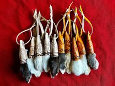 several different types of animal fur hanging from hooks on a red cloth covered tablecloth