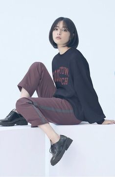 a woman sitting on top of a white block wearing black shoes and a t - shirt