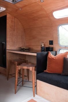 the interior of an rv with wood paneling and black couch, stools, and table