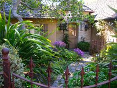 a garden with lots of plants and flowers in front of a house