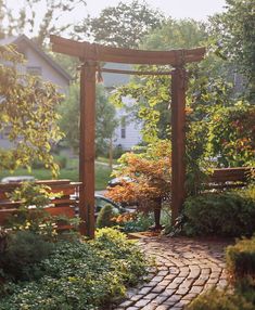 a brick pathway leads to a wooden arbor