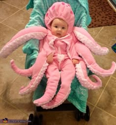 a baby in a pink octopus costume sitting on a stroller