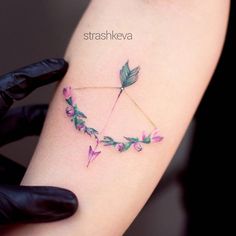 a woman's arm with an arrow and flowers on it