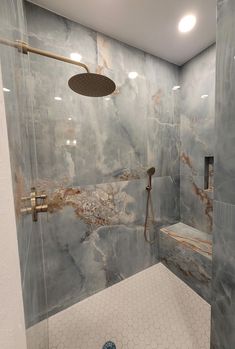 a bathroom with marbled walls and flooring, shower head and hand held faucet