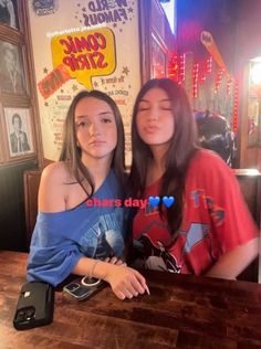 two young women sitting at a table in front of a sign that says comic strip