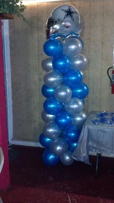 a tall balloon column is decorated with silver and blue balloons in the shape of an army helmet