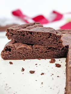 two pieces of chocolate brownie sitting on top of each other next to one another