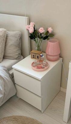 a white nightstand with pink flowers and a clock on it next to a night stand