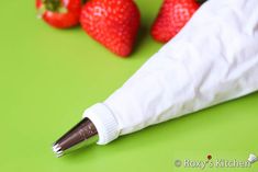 strawberries are sitting next to a white cloth and a pen on a green surface