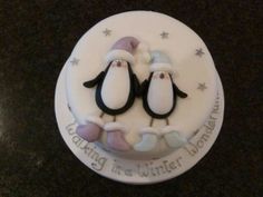 a cake decorated with two penguins wearing santa hats