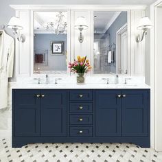 a bathroom with blue cabinets and white marble counter tops is pictured in this image, there are lights on either side of the sink