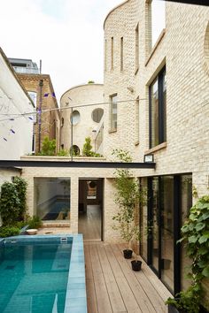 an indoor swimming pool in the middle of a courtyard with brick walls and large windows