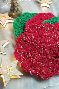 a crocheted red flower sitting on top of a table next to christmas decorations