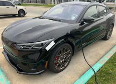 a black sports car plugged in to an electric charger