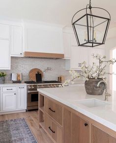 a large kitchen with white cabinets and wood accents on the countertops, along with a chandelier hanging from the ceiling