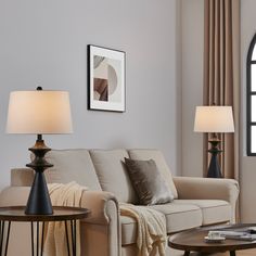 a living room filled with furniture and two lamps on top of tables in front of a window