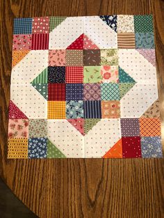 a close up of a patchwork quilt on a wooden table