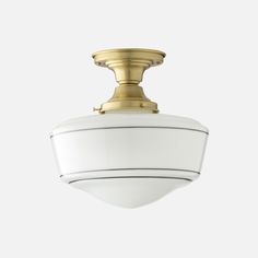 an overhead light fixture with a white glass shade on the top and gold trimming