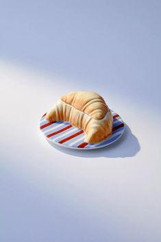 a croissant sitting on top of a plate with red, white and blue stripes