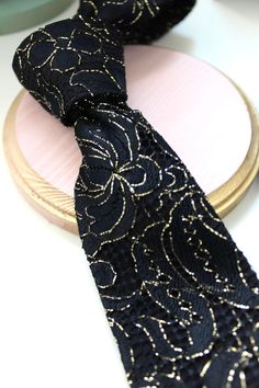 Black and Gold Trim Floral Lace Necktie I hand made this particular neck tie from a black floral lace with gold trim, and lined it with a soft black satin to keep in structured. I love this lace, and have been looking for something in this combo for a long time.  Tie measure 58" length and 2.75" at the widest point.  Handsome&Lace isn't an assembly line production company, nor do I scrimp on adding small details. I truly love what I do and make sure each and every layer and stitch is a representation of my integrity for uniqueness and ambition to be well tailored. For real.  From personally sourcing fabrics to hand cutting from handmade patterns, to ironing right here in studio playing the best music, and hand stitching over 450 tight invisible per tie! That's about 8 stitches an inch unli Elegant Gold Ties For Party, Elegant Patterned Ties For Semi-formal Occasions, Elegant Adjustable Black-tie Event Ties, Luxury Black Semi-formal Ties, Luxury Classic Patterned Ties, Luxury Patterned Ties For Semi-formal Occasions, Gold Tie, Custom Ties, Small Detail