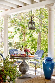 a blue vase sitting on top of a table under a white pergolated roof