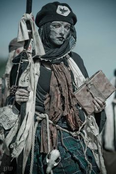 a woman dressed in costume holding a stick and some kind of bag on her shoulder