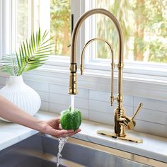 a person is washing their hands under a faucet in the kitchen sink with green soap