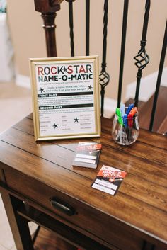 a wooden table with a sign and some pens on top of it next to a chair