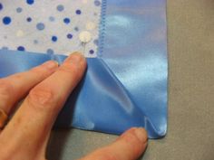 a person is sewing something on a piece of blue fabric with polka dots and a white flower