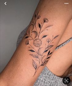 a woman's arm with flowers and leaves on it