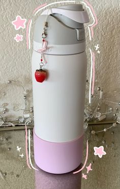 a pink and white container with a red apple hanging from it's side on a table