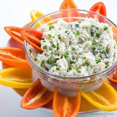 a bowl filled with carrots, celery and dip surrounded by sliced orange wedges