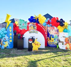 an assortment of pokemon themed birthday decorations in the grass with balloons and streamers around them