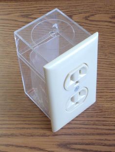 a plastic box with two white buttons on it sitting on a table next to a wooden surface