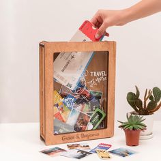 a person holding a credit card in front of a wooden box filled with travel cards