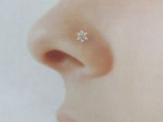 a close up of a person's nose with a single diamond earring on it