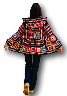 a woman is walking down the street wearing a colorful coat with an intricate design on it