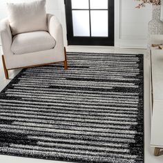 a black and white area rug in a living room with a chair next to it