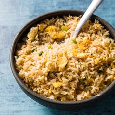 a bowl filled with rice and vegetables on top of a blue table