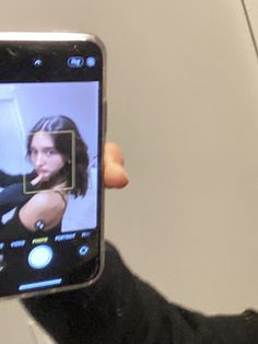 a person holding up a cell phone to take a selfie with her face on the screen