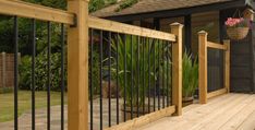 a wooden deck with wrought iron railing and potted plants