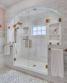 a bathroom with white tile and gold accents on the shower door, tub, and sink