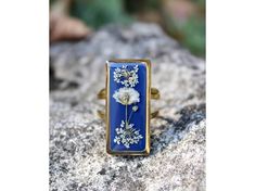 a blue and white flower ring sitting on top of a rock