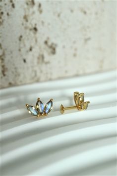 two pairs of earrings sitting on top of a white table next to a brick wall