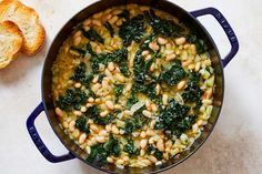 a pot filled with beans and greens next to some bread