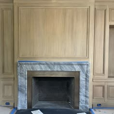 an empty fireplace in a room with wood paneling