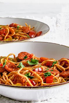 two white bowls filled with spaghetti and vegetables