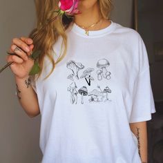 "Thank you for stopping by DreamOfTeezNyc Our Mushroom Garden Shirt is made-to-order just for you. Our shirts are super soft and comfy! Gildan tee puts a new spin on casual yet stylish.  👍🏻 WHAT YOU'LL GET A classic unisex short sleeve tee puts a new spin on casual comfort fits like a well-loved favorite. Made from very soft materials, this tee is 100% cotton for solid colors. The shoulders have twill tape for improved durability. There are no side seams. The collar is made with ribbed knitting to prevent curling damage.  👕 YOUR SHIRT IS .: 100% Cotton (fiber content may vary for different colors) .: Light fabric (4.5 oz/yd² (153 g/m .: Eurofit .: Tear away label .: Runs true to size 👉🏻 HOW TO ORDER 1. Please Check and Review all the Photos 2. Select your Shirt Color and Size from dro Relaxed Fit Short Sleeve Shirt With Mushroom Print, White Mushroom Print Top For Summer, Graphic Tee Shirt With Mushroom Print, White Short Sleeve Tops With Mushroom Print, Casual White Shirt With Mushroom Print, White Short Sleeve Top With Mushroom Print, White Cotton Tops With Mushroom Print, White Mushroom Print Short Sleeve Top, Spring White Tops With Mushroom Print