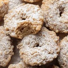 powdered sugar covered donuts sitting on top of a piece of parchment paper