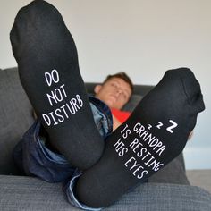 a person laying on top of a couch with their feet up in socks that say do not disturb resting eyes sockets